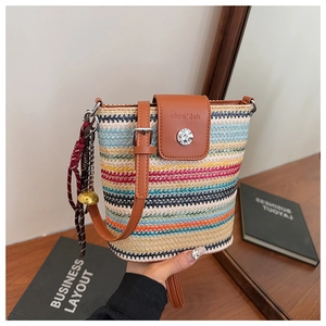 Détail d'un sac seau en paille tissée multicolore avec rabat cuir et grelot