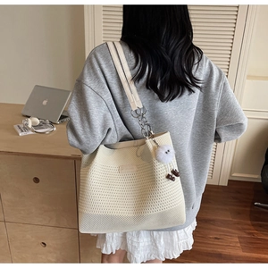 Détail du sac en tricot évidé avec bandoulière en chaîne et breloque peluche monstre