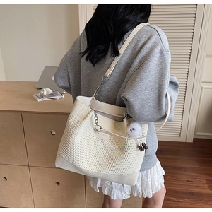 Détail du sac fourre-tout en maille crème avec bandoulière chaîne sur un mannequin