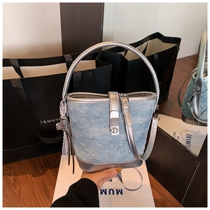 Dettaglio borsa a secchiello in denim azzurro con finiture in pelle argento e chiusura