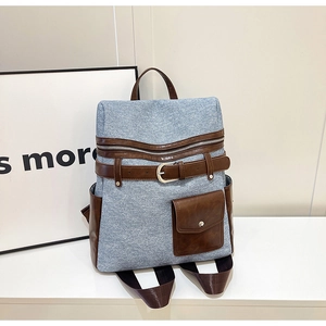 Detail of vintage denim backpack with brown leather patchwork and metal buckle accent