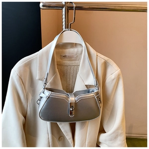 Detail of silver metallic leather handbag with a sleek metal clasp and curved minimalist design