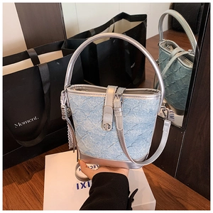 Dettaglio della borsa a secchiello in denim celeste con finiture in pelle argento e chiusura