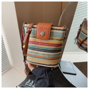Détail du sac seau en paille tissée colorée avec rabat en cuir brun et boucle métallique