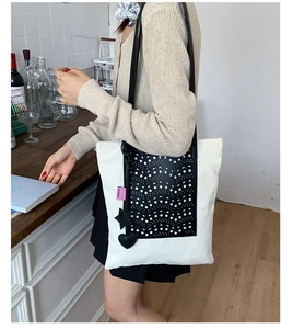 Detail of contrast color tote bag featuring black laser-cut floral patterns and star charms