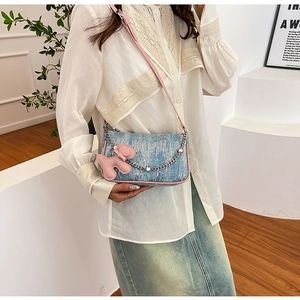 Close-up of blue sequin denim shoulder bag featuring pink trim and a cute puppy charm
