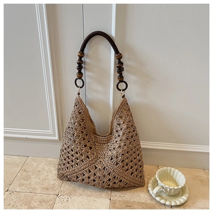 Detail of hand-woven straw tote bag with round brown wooden beads on the handle