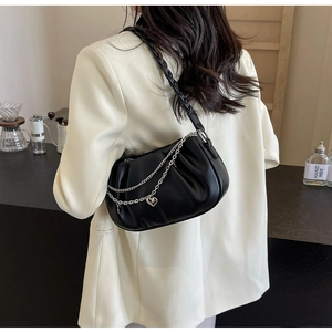 Détail du sac nuage plissé noir avec chaîne argentée, pendentif cœur et bandoulière tissée