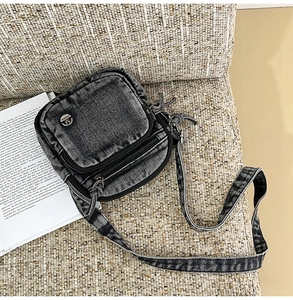Détail d'un sac bandoulière en denim gris foncé vintage avec fermetures éclair et sangle