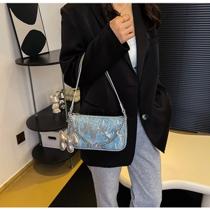 Detail of light blue sequin underarm bag with silver chain and cute bear charm