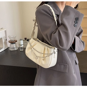 Détail du sac nuage crème avec chaîne cœur en métal et bandoulière en cuir tressé