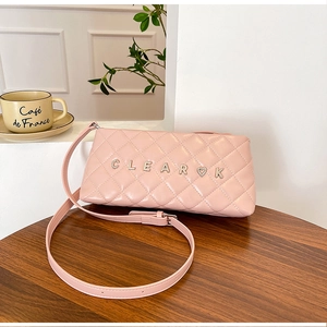 Detailed view of pink quilted leather bag with silver metal letters and heart charm