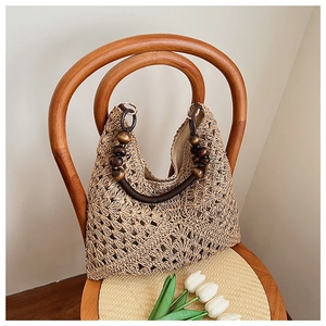 Detail of hand-woven straw tote bag with round brown wooden bead handles on a chair