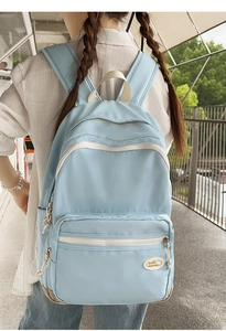 Outdoor shot of a light blue casual backpack featuring a stylish cream-colored contrast handle