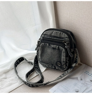 Détail macro du sac bandoulière en denim noir délavé avec double fermeture éclair