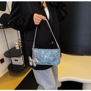 Detail of blue denim shoulder bag featuring silver sequins and a metallic balloon dog charm