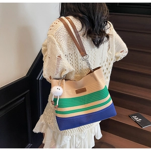 Détail d'un sac cabas en maille rayée avec bandoulière en cuir et charm peluche