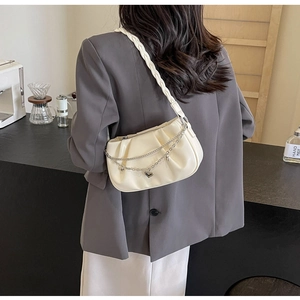 Vue latérale du sac sous le bras plissé crème avec chaîne et pendentif cœur