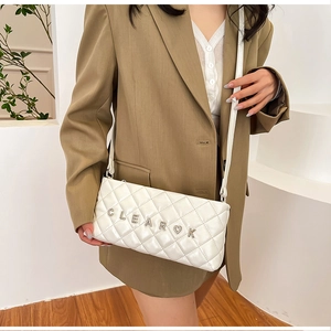 Detail of white quilted crossbody bag featuring CLEAROK metal letters and heart charm