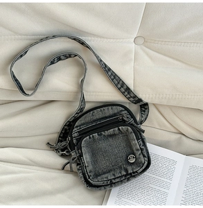 Détail du sac bandoulière en denim délavé gris foncé avec logo métallique M FASHION