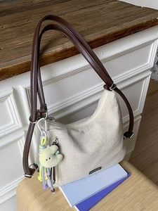 Vintage beige canvas shoulder tote bag with brown straps and plush charms for commuting
