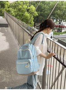 Detail view of the light blue backpack with reinforced brown base and cream straps