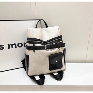 Detail of cream canvas backpack with black leather straps and silver metal buckle