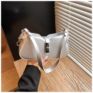 Detail of silver metallic shoulder bag showing wave-shaped edge and twist-lock buckle