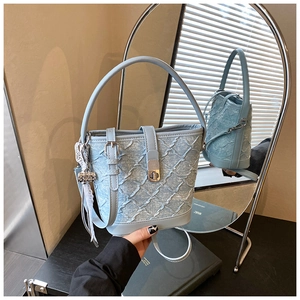 Dettaglio borsa a secchiello in denim azzurro con texture trapuntata e chiusura silver