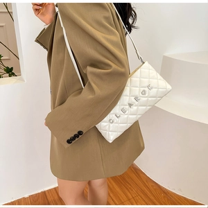 Close-up of white quilted chain bag with silver CLEARK metal logo on female model