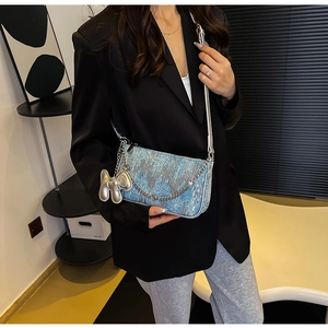 Detail of light blue sequined shoulder bag featuring a silver balloon dog charm and chain