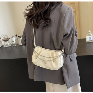 Détail d'un sac nuage plissé blanc crème avec chaînes à breloques cœur argentées