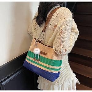Détail du sac cabas en tricot rayé avec étiquette en cuir et accessoire en peluche