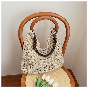 Detail of hand-woven floral patterns on a beige tote bag with wooden bead handles