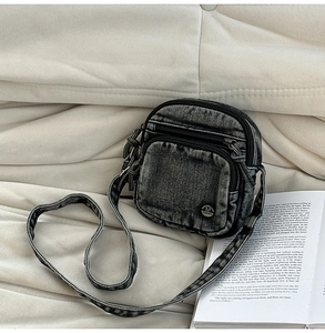 Détail d'un sac bandoulière vintage en jean avec fermetures éclair sur fond de tissu doux
