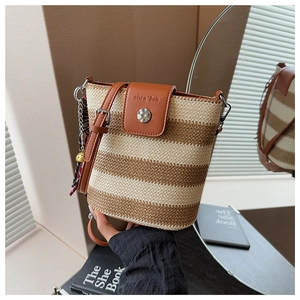 Détail du sac seau en paille tissée avec rabat en cuir marron et boucle argentée