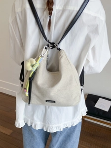 Beige canvas convertible tote backpack with black leather straps and moon charm