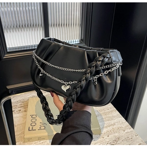 Détail du sac plissé noir avec poignée tressée et chaînes argentées à breloques cœur