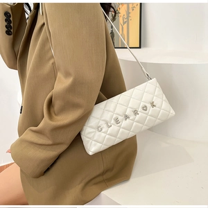 Detail of white quilted handbag featuring silver CLEAROK metallic lettering and heart accent