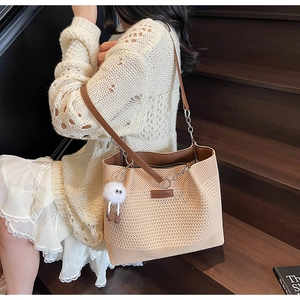 Détail du sac cabas beige tressé avec bandoulière en cuir brun et pendentif blanc
