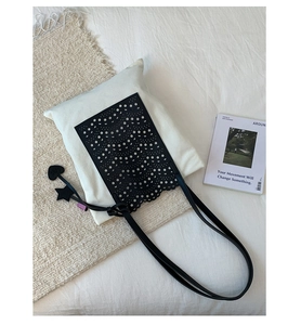 Detail of laser-cut wave pattern on black tote bag with star and heart charms