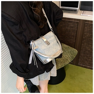 Dettaglio della borsa a secchiello in denim azzurro con pizzo e finiture metallizzate