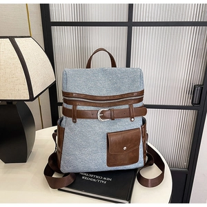 Detail view of denim fabric and brown leather straps on a vintage backpack