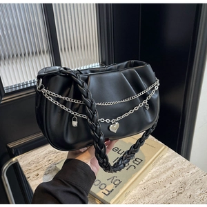 Détail d'un sac nuage plissé noir avec poignée tressée et chaîne à breloque cœur