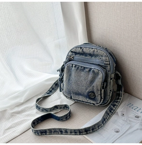 Vue détaillée de la texture denim bleu délavé et du logo métallique sur le sac bandoulière