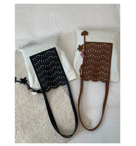 Detail of black and brown laser-cut handbags with wave edges and star heart charms