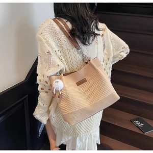 Détail du sac cabas beige tissé avec bandoulière en cuir marron et pendentif en peluche