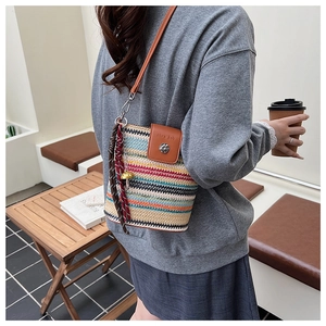 Détail du sac seau tissé avec rabat en cuir, fermoir en métal et pompon à franges