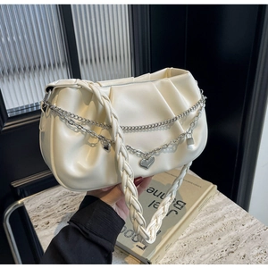Détail du sac nuage crème avec chaîne cœur argentée et anse tressée sur fond de marbre
