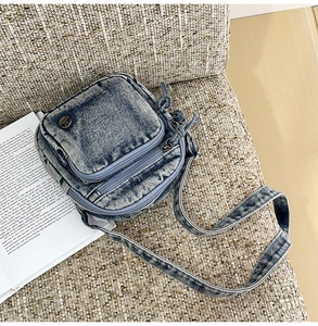 Détail d'un petit sac bandoulière en denim bleu avec plusieurs poches sur lin rustique